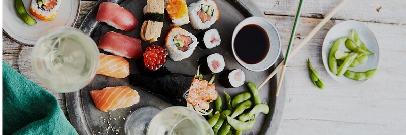 Een schaal met verschillende sushi en soja boontjes